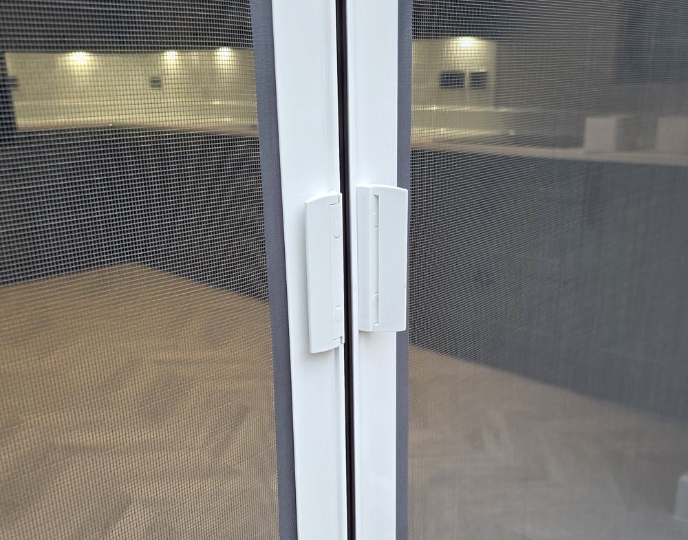 Magnetic closing strip where two roller door screens meet