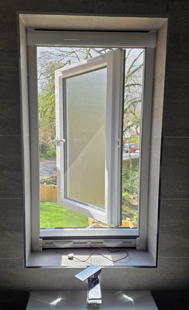 Roller fly screen fitted in a window reveal with the mesh pulled down