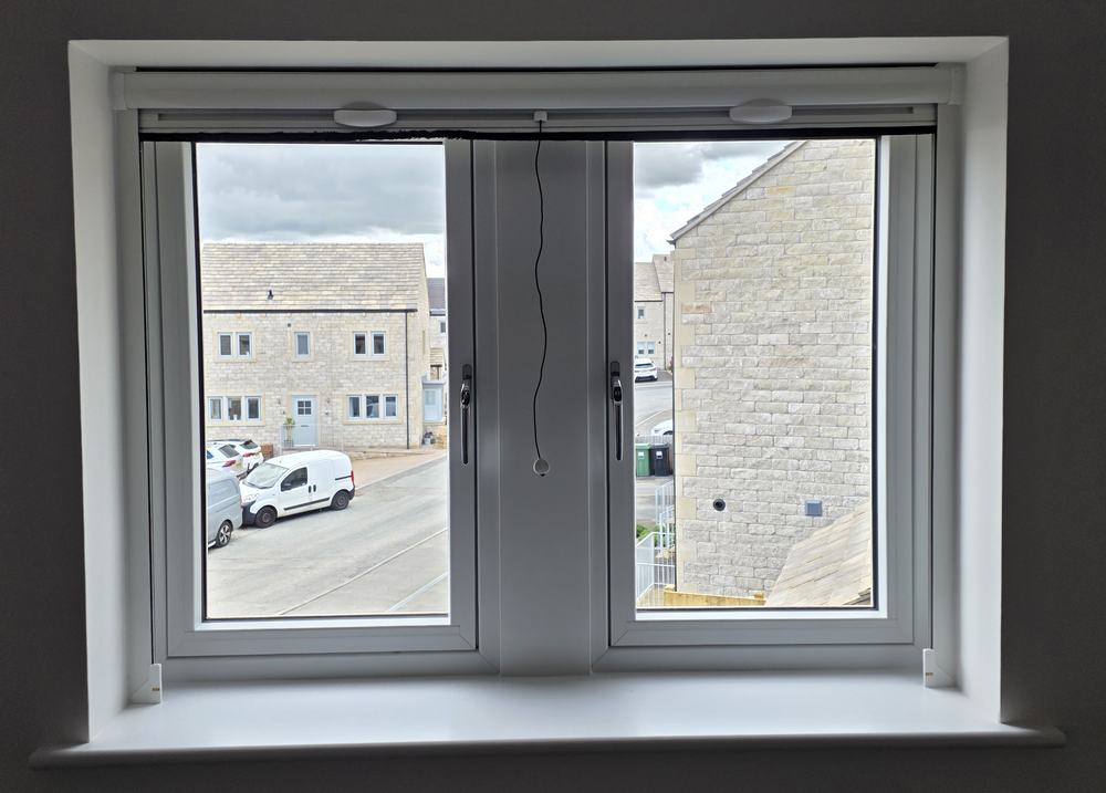 Slim roller fly screen cassette above a window with the mesh pulled down